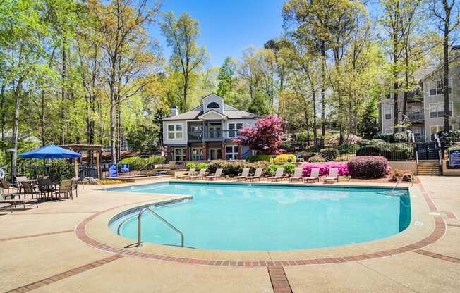 Apartments in Marietta Georgia for Rent – Wood Pointe Apartments - A large swimming pool surrounded by trees and a building in the background.