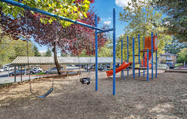 A playground with a swing set and a red slide.