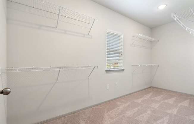 the spacious closet in our 2nd bedroom with hanging racks and a window