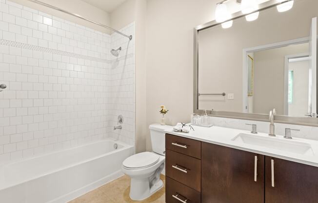 Spacious bathroom with tiled shower, bathtub, and updated vanity area with above-mirror lighting at Sylvan Uptown,Colorado, Denver