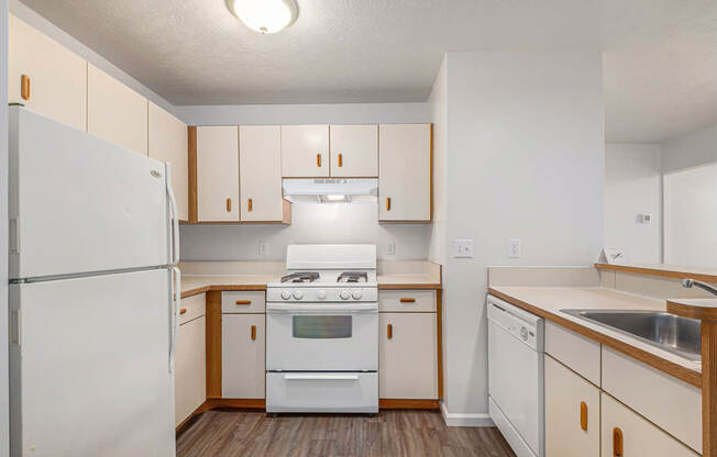 A kitchen with white appliances and a breakfast bar at Brentwood Park Apartments in LaVista, NE