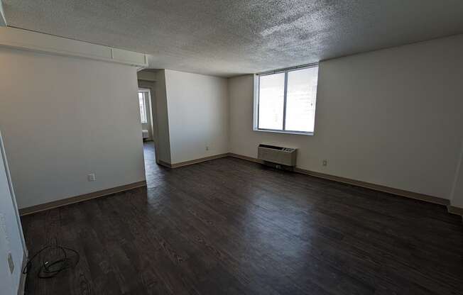 an empty living room with wooden floors and a window