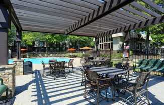 a patio with tables and chairs next to a swimming pool at Elea Apartments in Marietta, GA