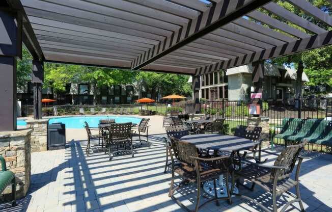 a patio with tables and chairs next to a swimming pool at Elea Apartments in Marietta, GA