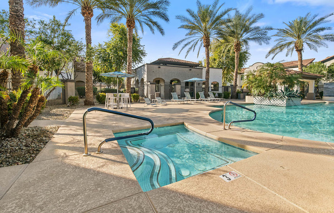 A pool surrounded by palm trees and a building in the background.