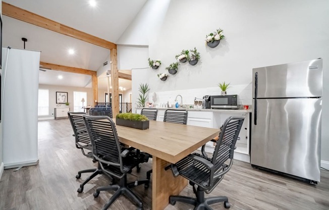 a dining room with a table and chairs and a kitchen with stainless steel appliances