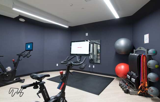 a fitness room with exercise equipment and a large screen