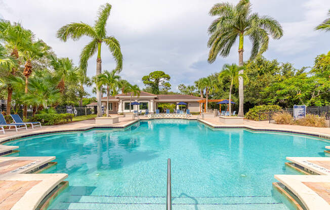 a large swimming pool with palm trees in the background at Heritage Bay, Jensen Beach, FL