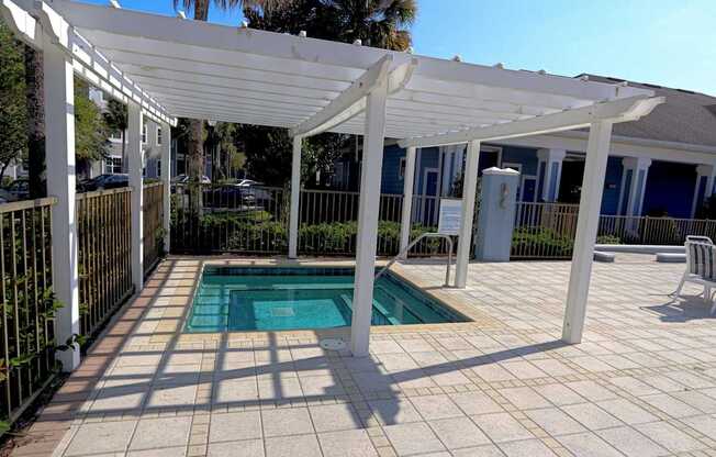 A pool under a white pergola on a sunny day.