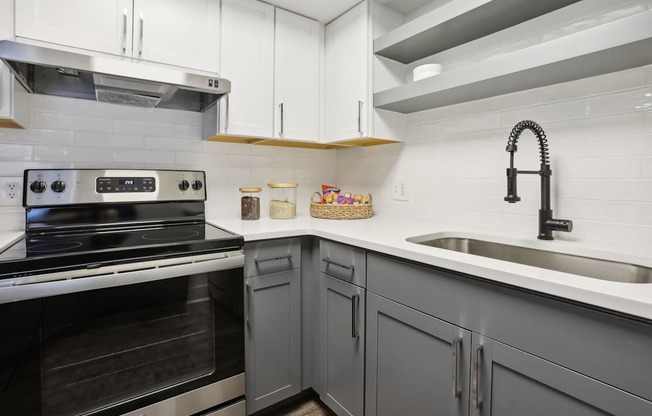 A modern kitchen with a stove, sink, and cabinets.