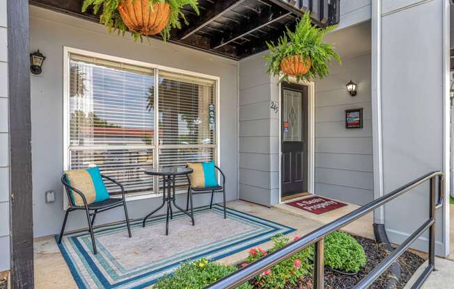 a porch with two chairs and a table and a door