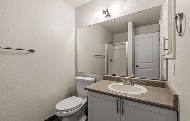 A bathroom with a toilet, sink, and mirror.