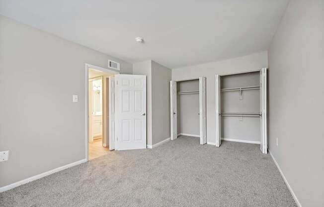 a bedroom with a carpeted floor and two closet doors at ReNew Odenton