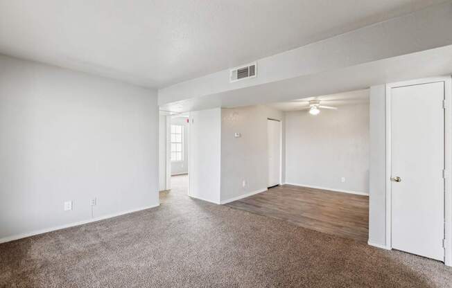 A spacious room with white walls and a brown carpet.