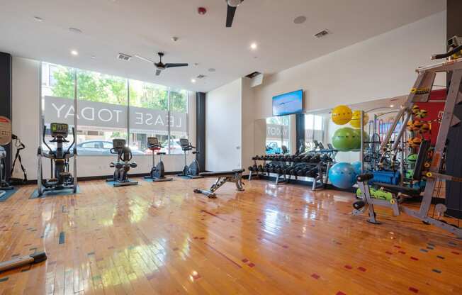 a workout room with weights and cardio machines and a large window