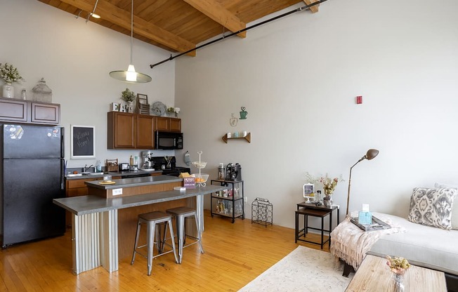 A kitchen with a black refrigerator and a white couch.