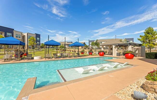 A swimming pool with a glass divider in the middle and a blue umbrella on the left.