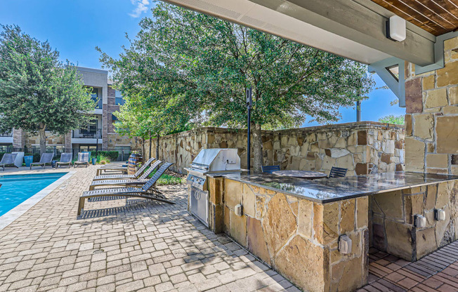 an outdoor kitchen with a grill and a swimming pool at Discovery at Craig Ranch, Texas, 75070