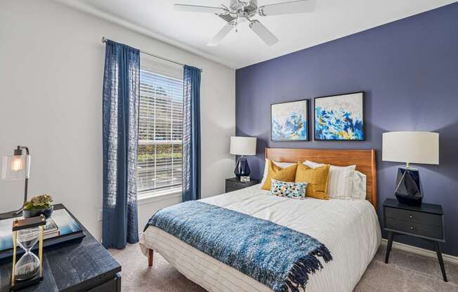A bedroom with a bed, nightstands, and a ceiling fan.