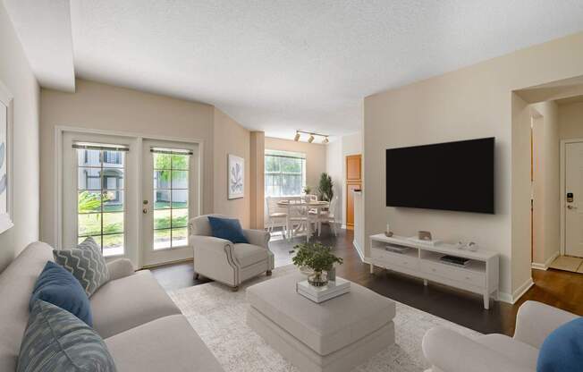 A living room with a white couch, a white coffee table, and a black television.