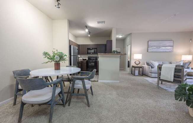 A modern living room with a dining table and grey chairs.