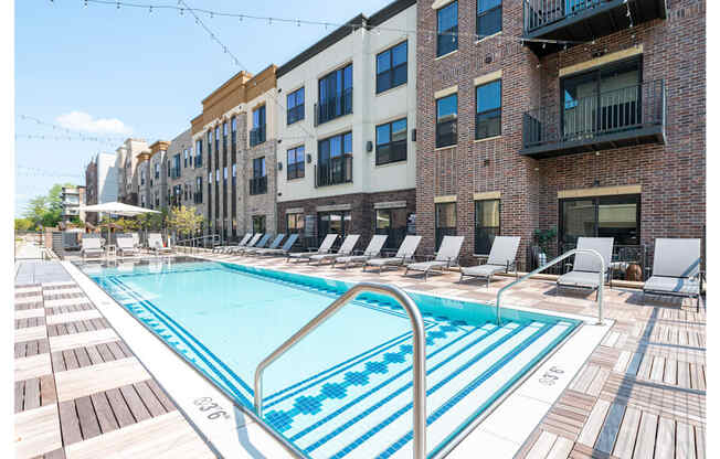 A swimming pool surrounded by lounge chairs and buildings.