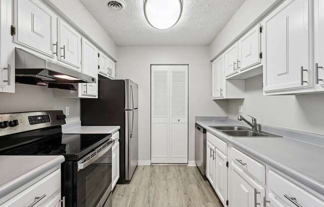 A kitchen with white cabinets and black countertops.