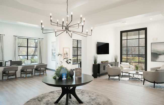 A modern living room with a black chandelier and a round table with a vase of flowers on it.