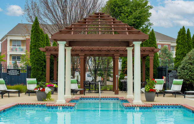 a wooden gazebo with pillars next to a swimming pool