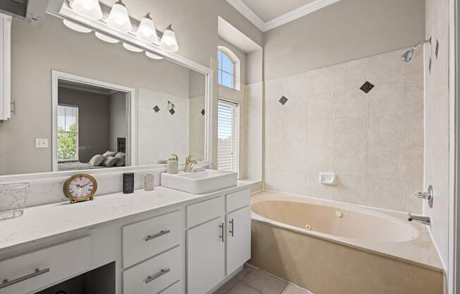 A bathroom with a tub, sink, and mirror.