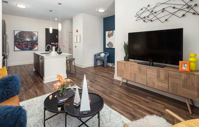 a living room and kitchen with a large tv and a table