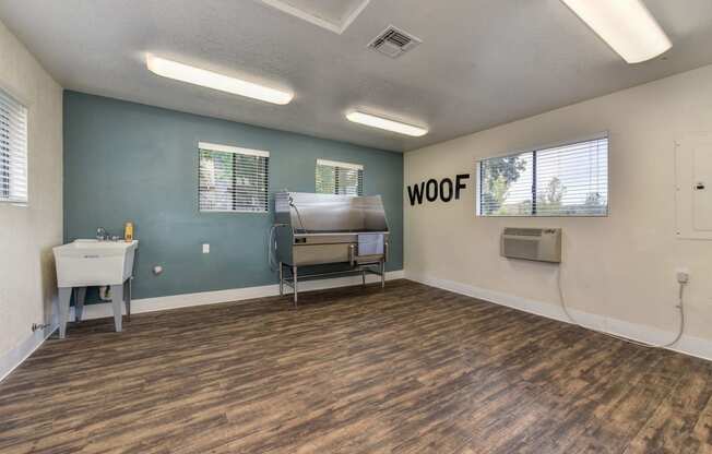 Dog Spa Tub with Sink, Hardwood Inspired Floor, Dog Washing Tub, WOOF Written in Black Letters on Wall, and Fluorescent Lights