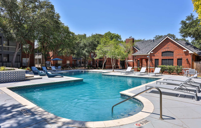 A swimming pool surrounded by lounge chairs and trees.