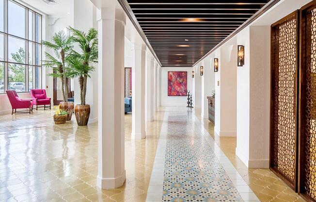 A long hallway with a tile floor and a red chair.