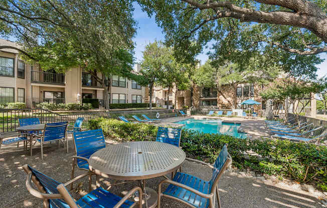 A patio with a table and chairs overlooking a pool.