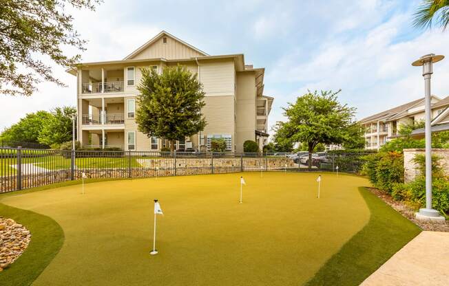 a putting green with a building in the background