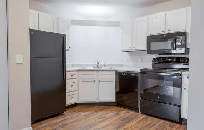 an empty kitchen with black appliances and white cabinets