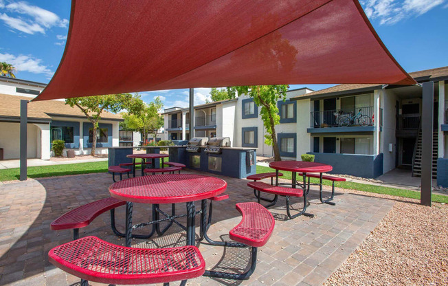 a covered patio with red tables and chairs