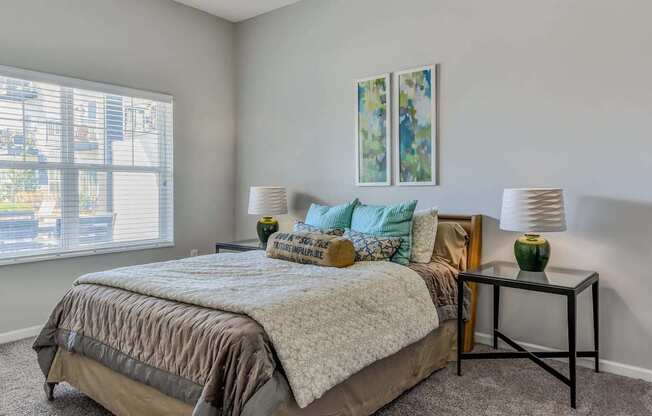 A bedroom with a large bed and two lamps.