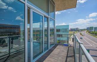 a balcony with glass doors and a view of the city