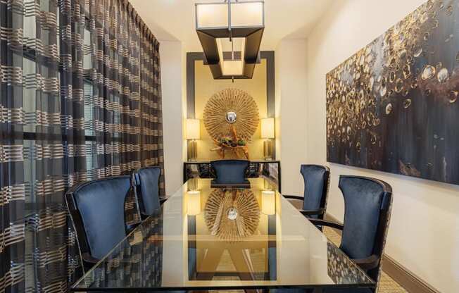 a dining room with a long glass table and blue chairs