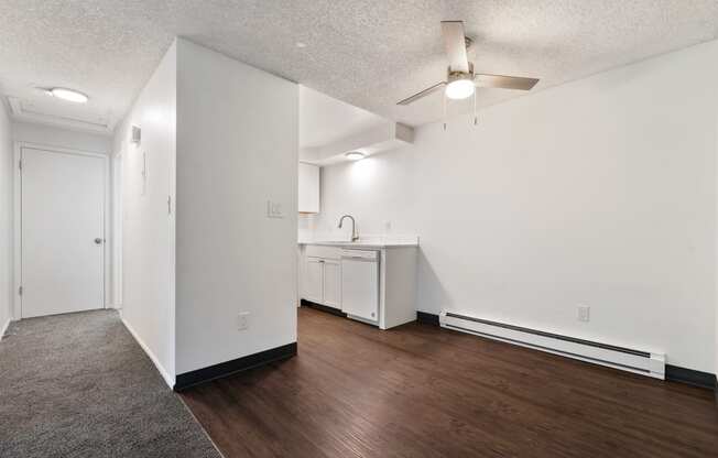 an empty living room and kitchen with white walls and wood flooring