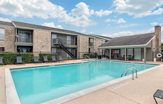 Swimming Pool and Sun Deck with Lounge Chairs with Trees and Building Exteriors in the Background