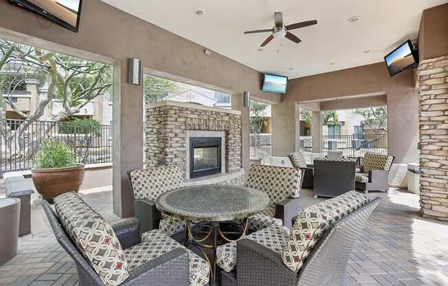 A patio with a table, chairs, and a fireplace.