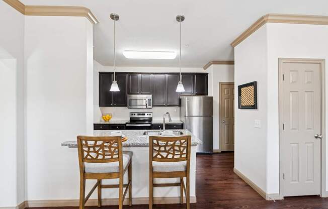 A kitchen with a table and two chairs.