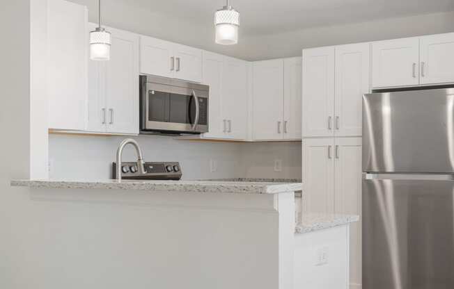 an empty kitchen with white cabinets and a stainless steel refrigerator