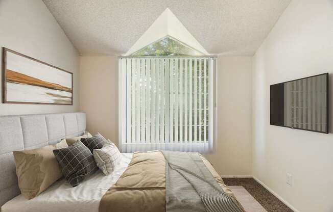 A bedroom with a bed, pillows, and a painting on the wall.