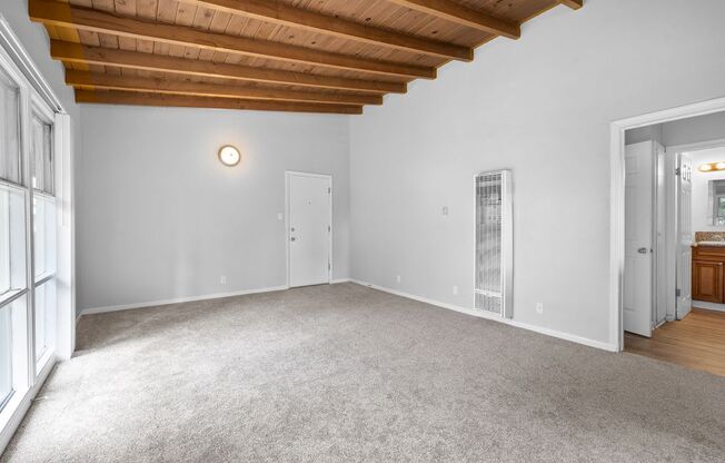 a living room with carpet and a door to a bathroom