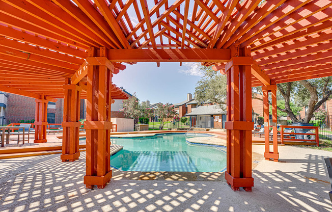 a backyard with a pool and a wooden pergola