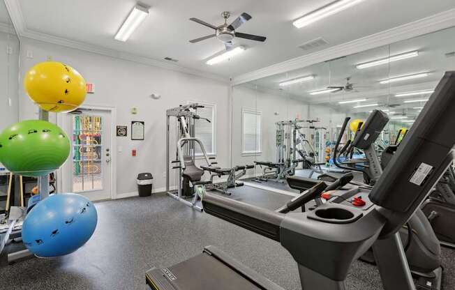 A gym with a treadmill, exercise balls, and other equipment.